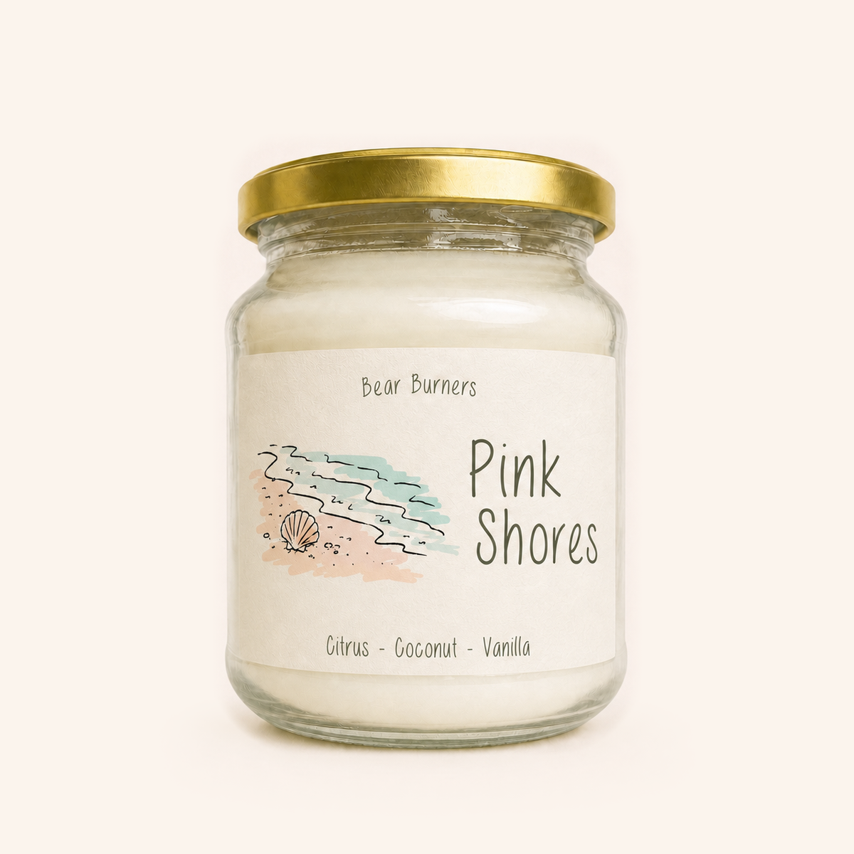 Pink Shores candle in a clear glass jar with a gold lid and illustrated cream label.