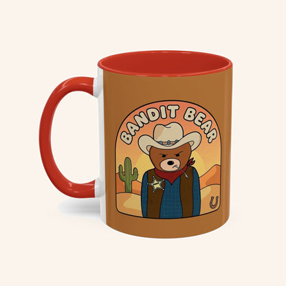 Bandit mug with a cowboy bear portrait, warm brown artwork and red handle.