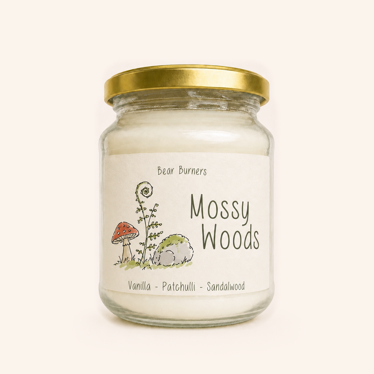 Mossy Woods candle in a clear glass jar with a gold lid and illustrated cream label.