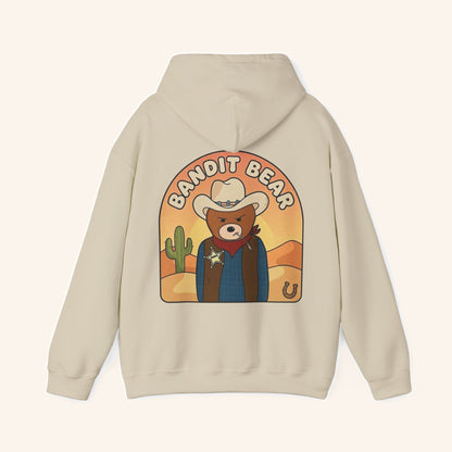 Back of a cream hoodie with a large Bandit Bear cowboy illustration.