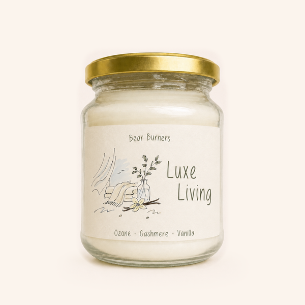 Luxe Living candle in a clear glass jar with a gold lid and illustrated cream label.