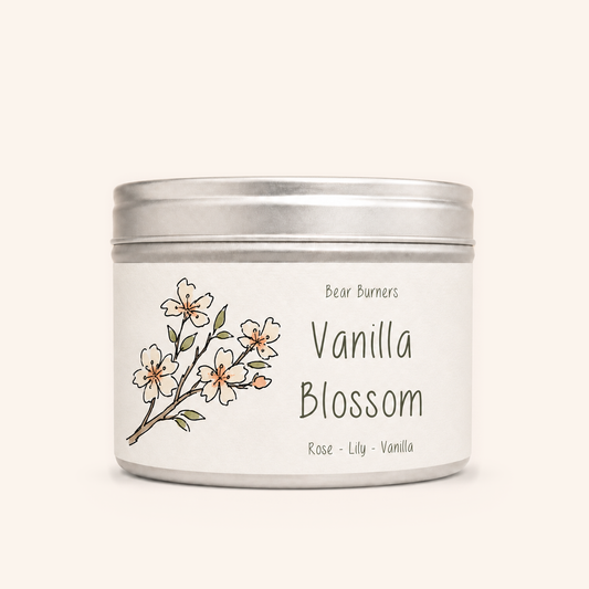 Vanilla Blossom candle in a silver lidded tin with an illustrated cream label.