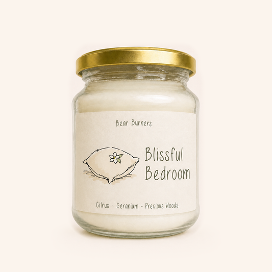 Blissful Bedroom candle in a clear glass jar with a gold lid and illustrated cream label.