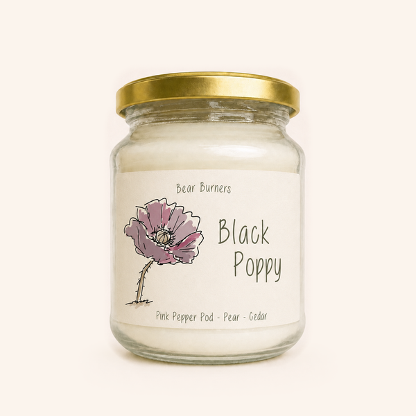 Black Poppy candle in a clear glass jar with a gold lid and illustrated cream label.