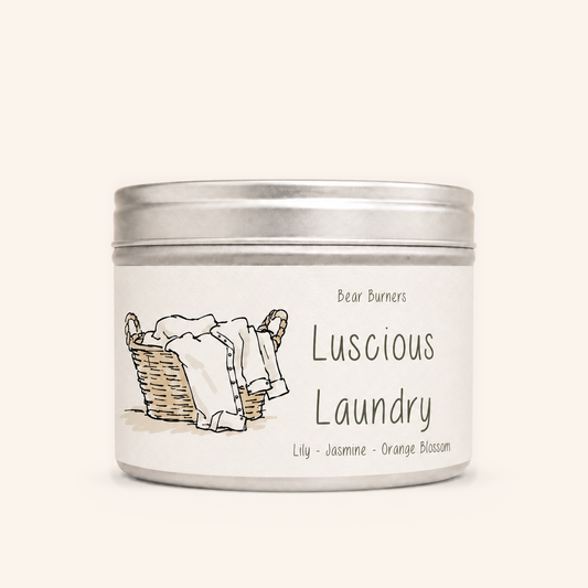 Luscious Laundry candle in a silver lidded tin with an illustrated cream label.