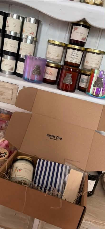 An open Candle Club box in front of a customer's candle collection