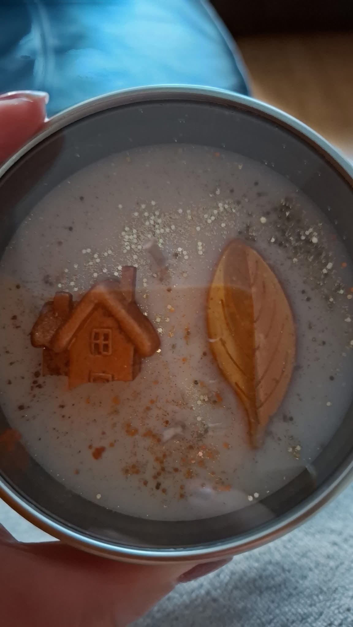 Close-up of a decorated Candle Club tin candle with a wax house and leaf
