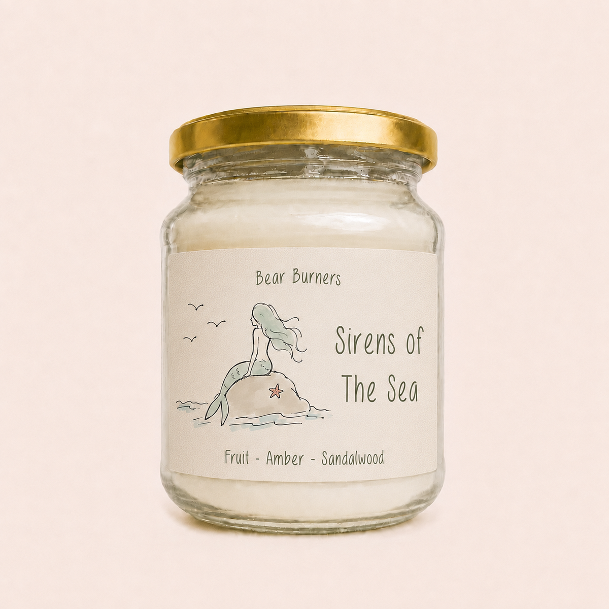 Sirens of the Sea candle in a clear glass jar with a gold lid and mermaid label.