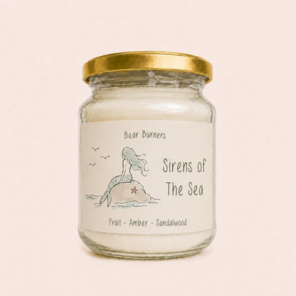 Sirens of the Sea candle in a clear glass jar with a gold lid and mermaid label.