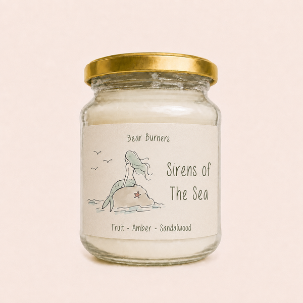 Sirens of the Sea candle in a clear glass jar with a gold lid and mermaid label.